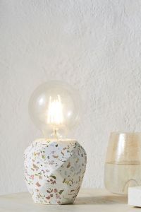 A medium-sized table-top lamp with a geometric, terrazzo base and large Edison-style light bulb.
