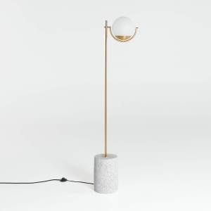 A corded, stand-up floor lamp featuring a terrazzo base, brass post and globe light.